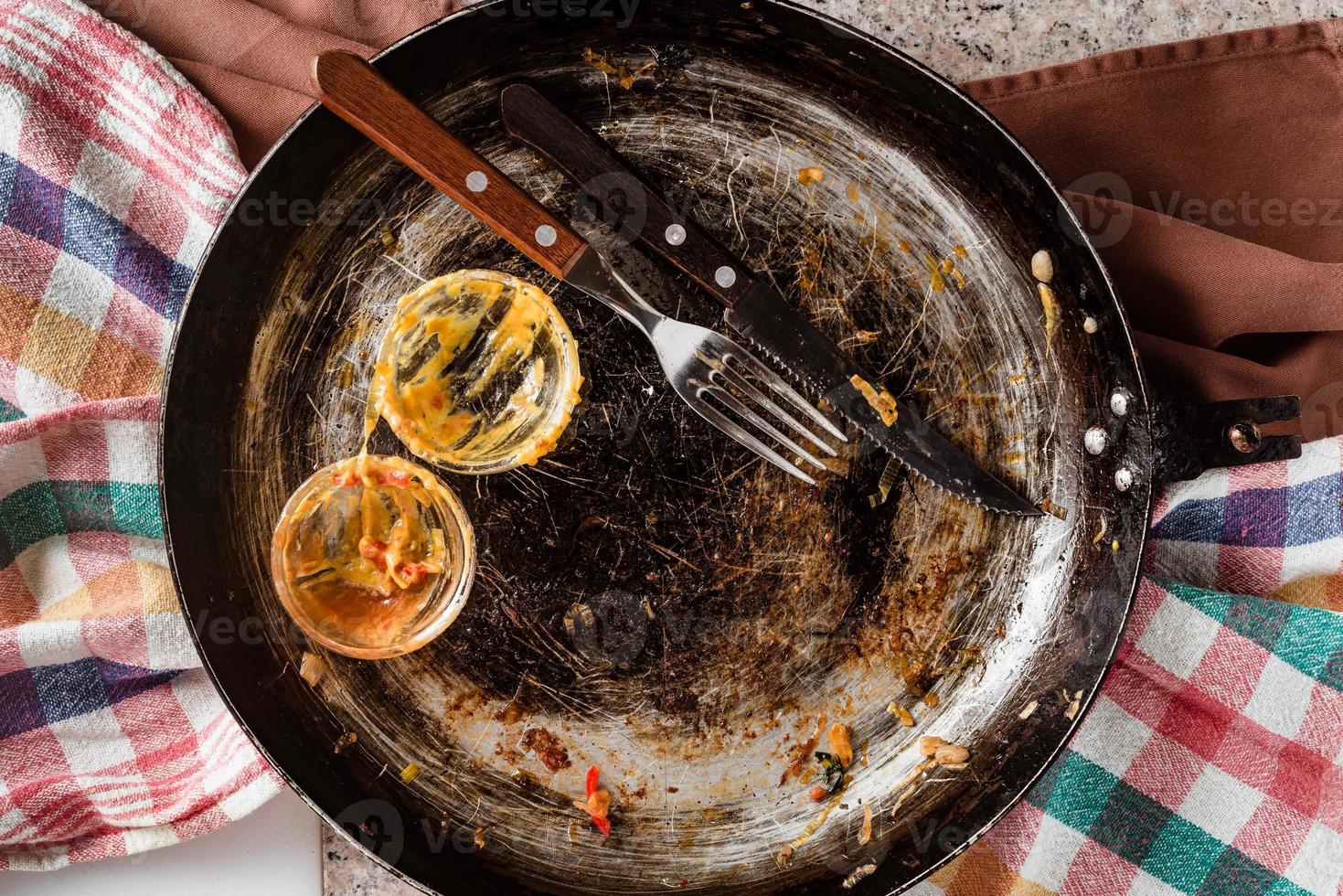 leeres schmutziges Geschirr, Ende des köstlichen Essens, rustikale Pfanne, Gabel und Messer und leere Schüssel mit Senf und Ketchup. foto