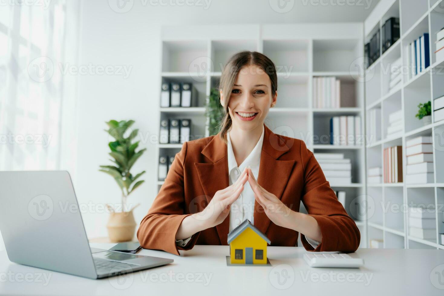 weibliche immobilienmakler verwenden hände, um das rote dach für das konzept der immobilieninvestition über den haushandel, den kauf am schreibtisch im büro zu schützen foto