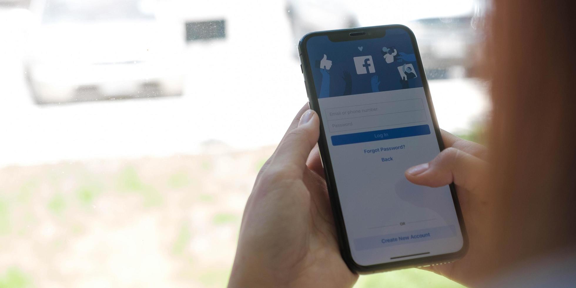 chiang mai, thailand 18. august 2020 - frau, die ein iphone x mit sozialem internetdienst facebook auf dem bildschirm hält. foto