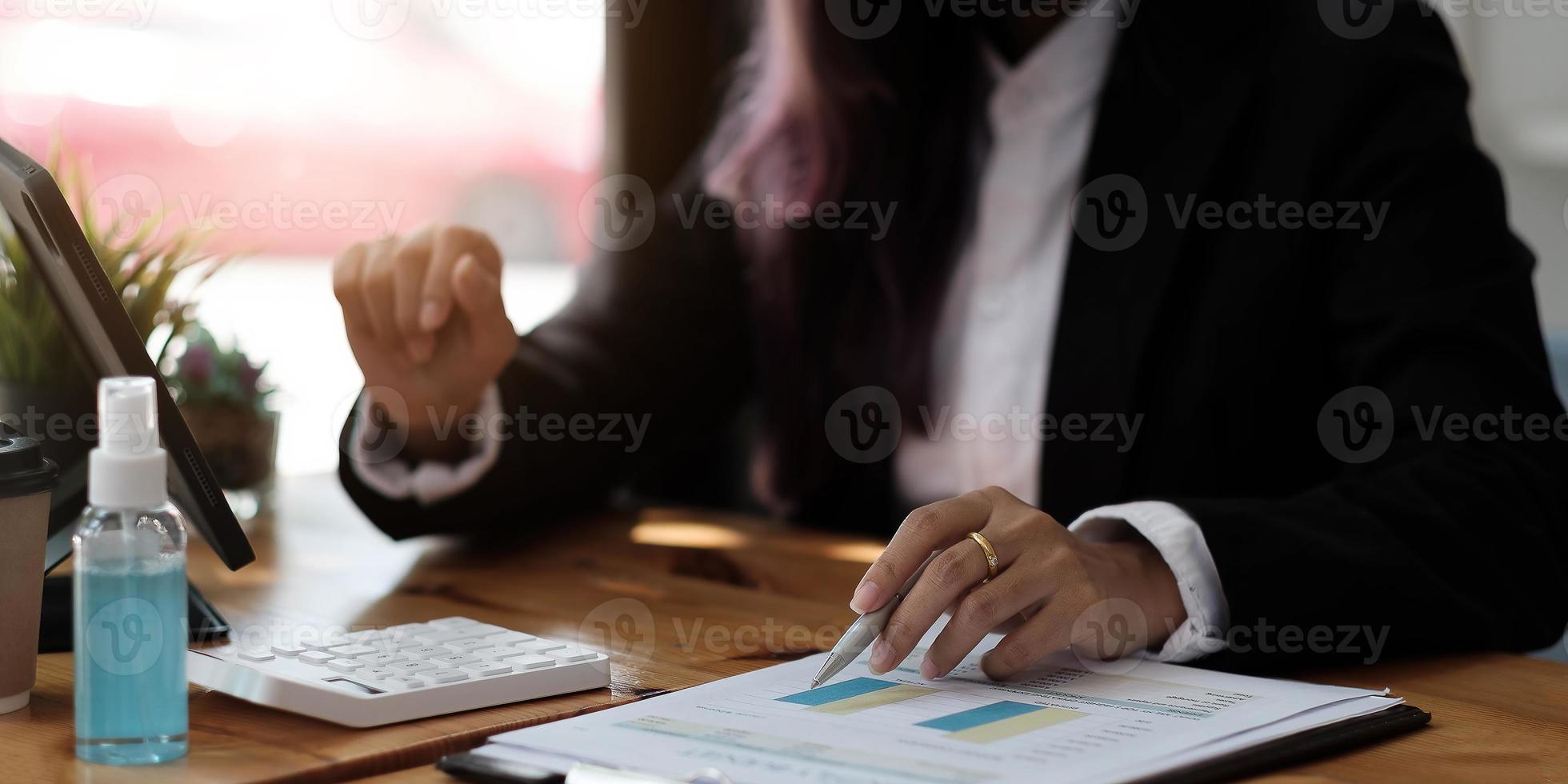 Geschäftsfrau mit Taschenrechner für Mathe-Finanzierung auf Holzschreibtisch im Büro- und Geschäftshintergrund, Steuern, Buchhaltung, Statistik und analytisches Forschungskonzept foto