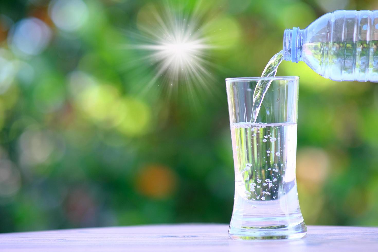 Wasser fließt in ein Glas auf Tisch und Mineralwasser Gesundheitskonzept foto