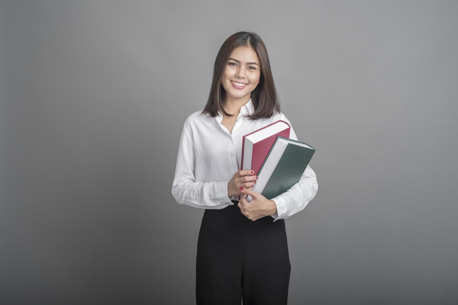 schöne Lehrerin mit Buch auf grauem Hintergrund foto