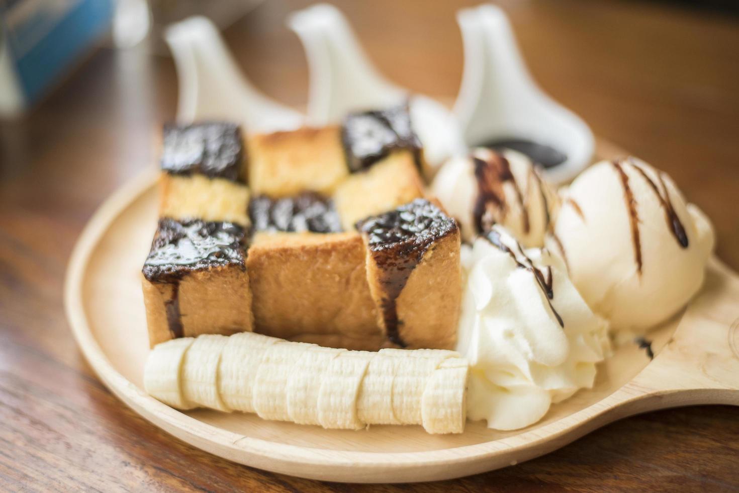 Honigtoast mit Vanilleeis, Schlagsahne und Schokoladensirup. serviert mit Banane foto