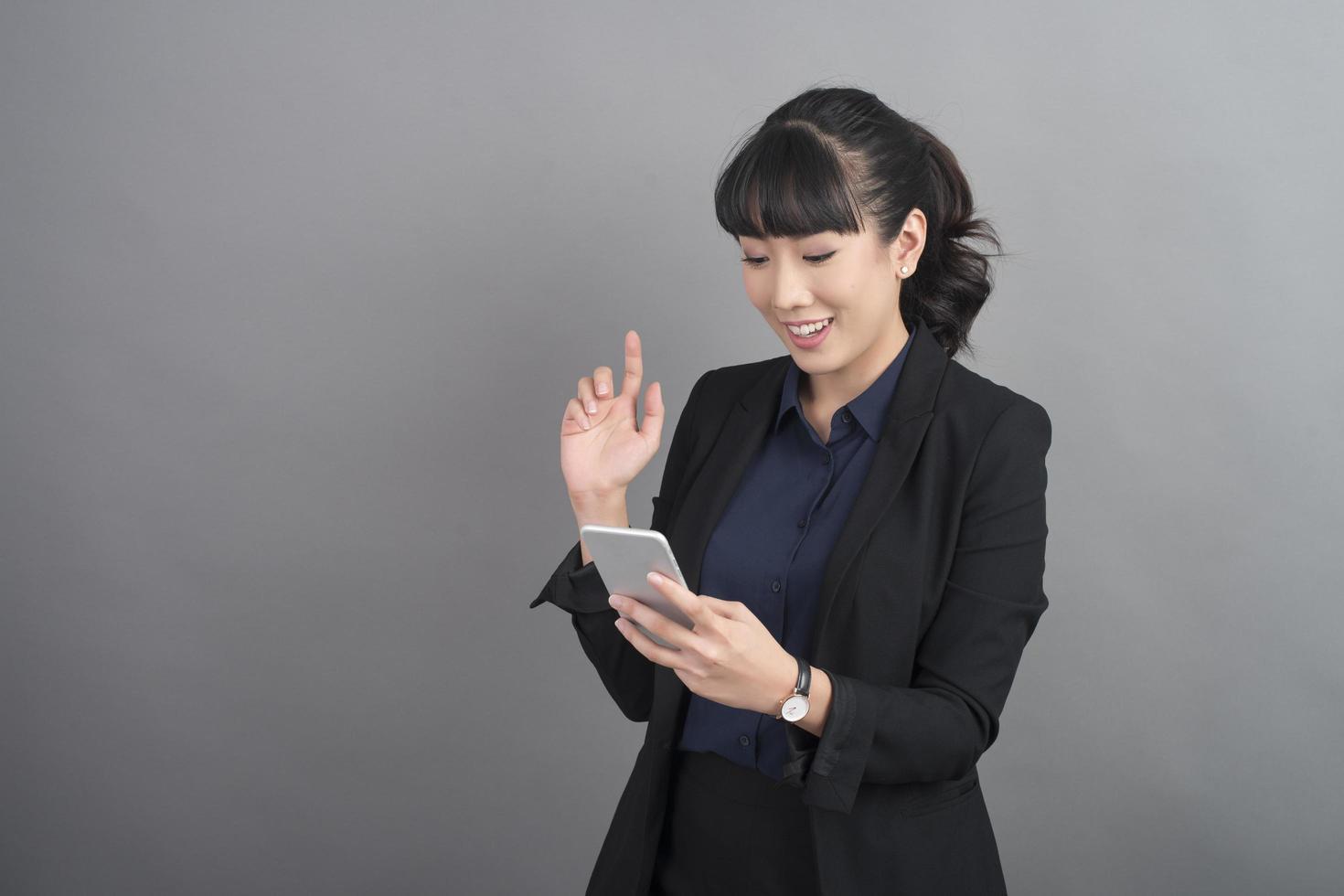 schöne Geschäftsfrau mit Smartphone auf grauem Hintergrund foto