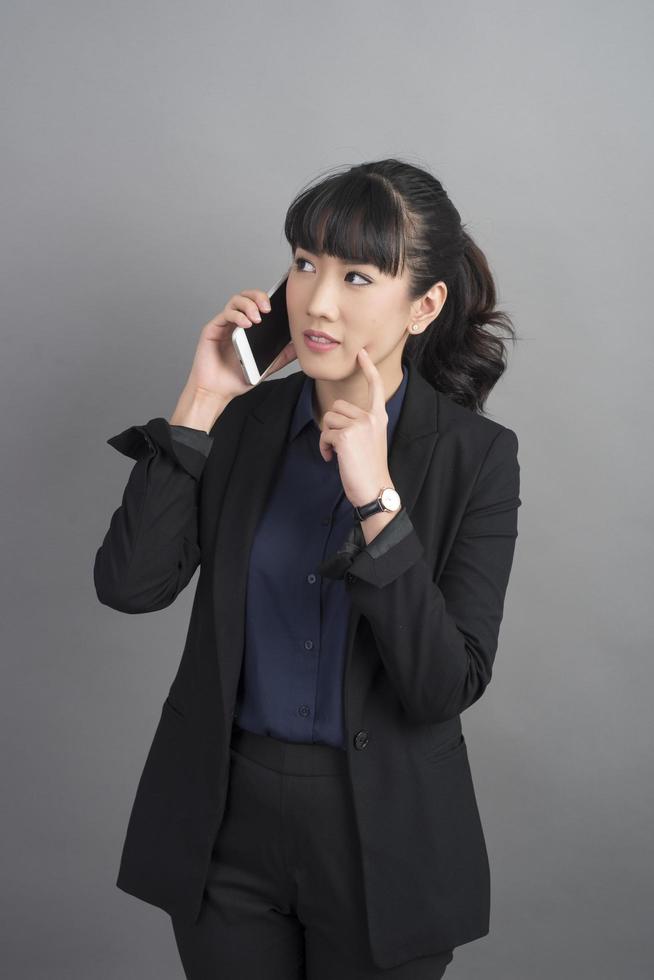 schöne Geschäftsfrau mit Smartphone auf grauem Hintergrund foto