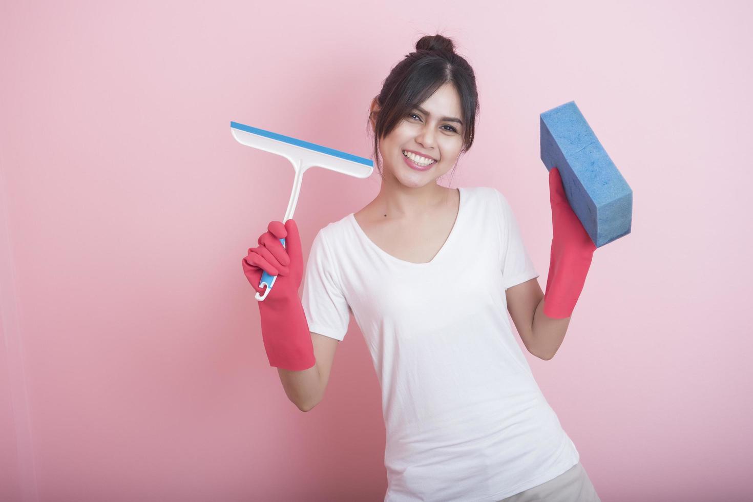 schöne asiatische Hausfrau, die auf rosa Hintergrund lächelt foto