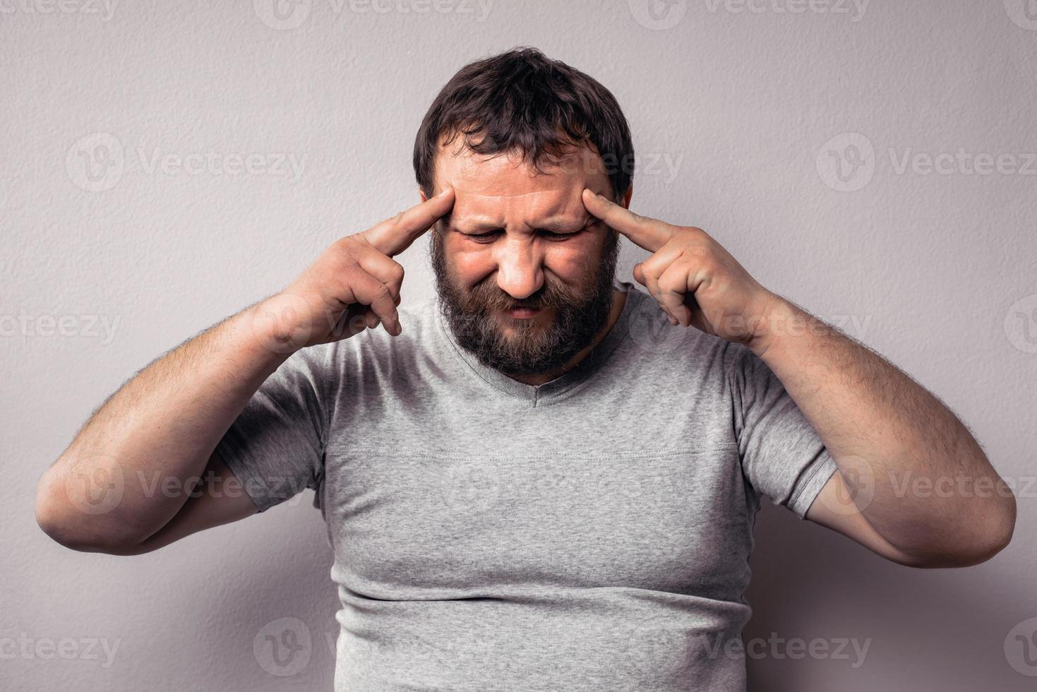 Frustrierter bärtiger Mann, der seinen Kopf mit den Händen berührt foto