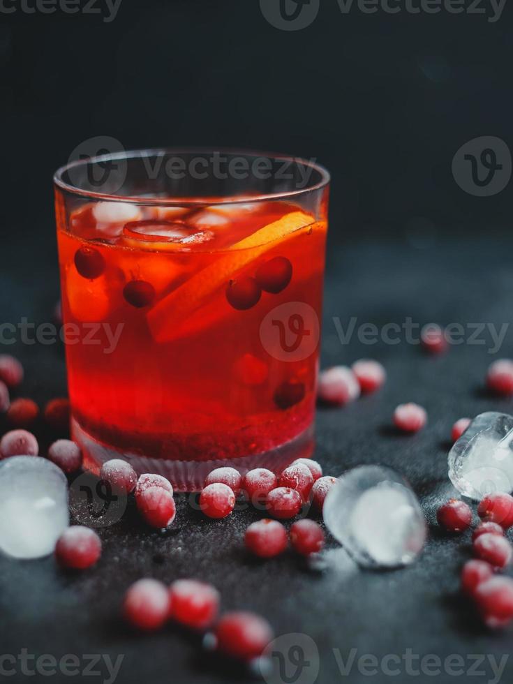 Aperol Spritz mit Eis und Preiselbeeren auf schwarzem Hintergrund. foto