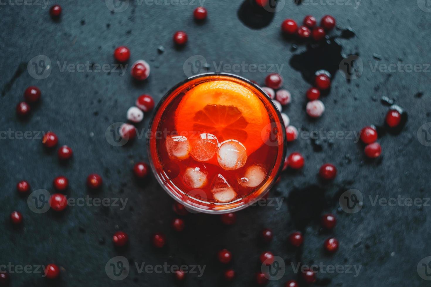 Aperol Spritz mit Eis und Preiselbeeren auf schwarzem Hintergrund. foto