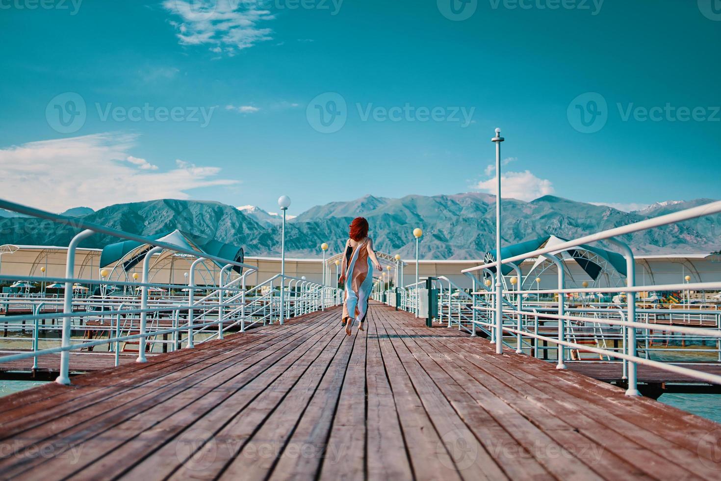 Rothaariges Mädchen läuft am Pier entlang. foto