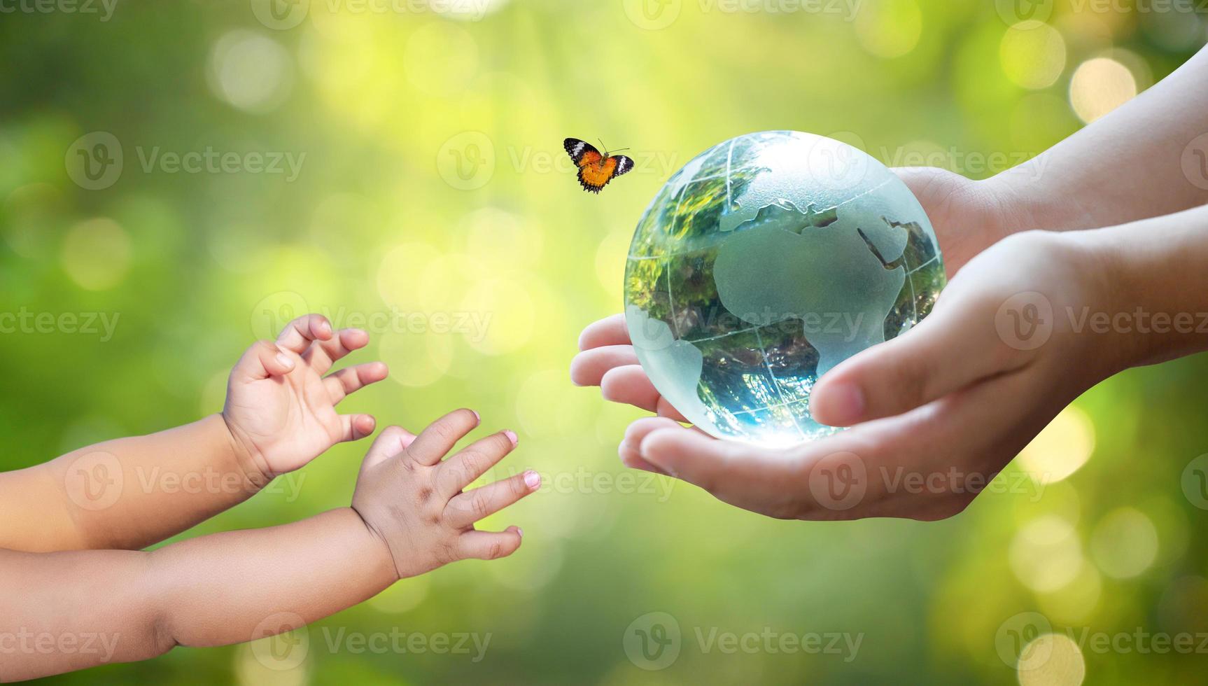 Erwachsene schicken Babys die Welt. Konzepttag Erde rette die Welt rette die Umwelt Die Welt liegt im Gras des grünen Bokeh-Hintergrunds foto