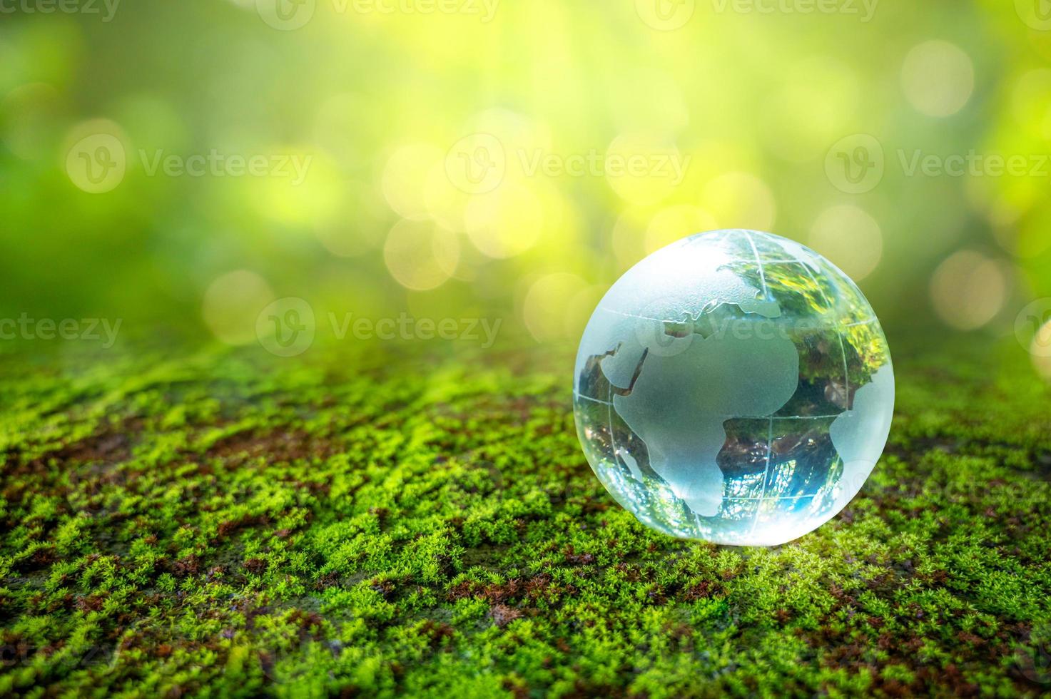 ein mann mit einem glaskugelkonzept tag erde rette die welt rette die umwelt die welt ist im gras des grünen bokeh-hintergrundes foto