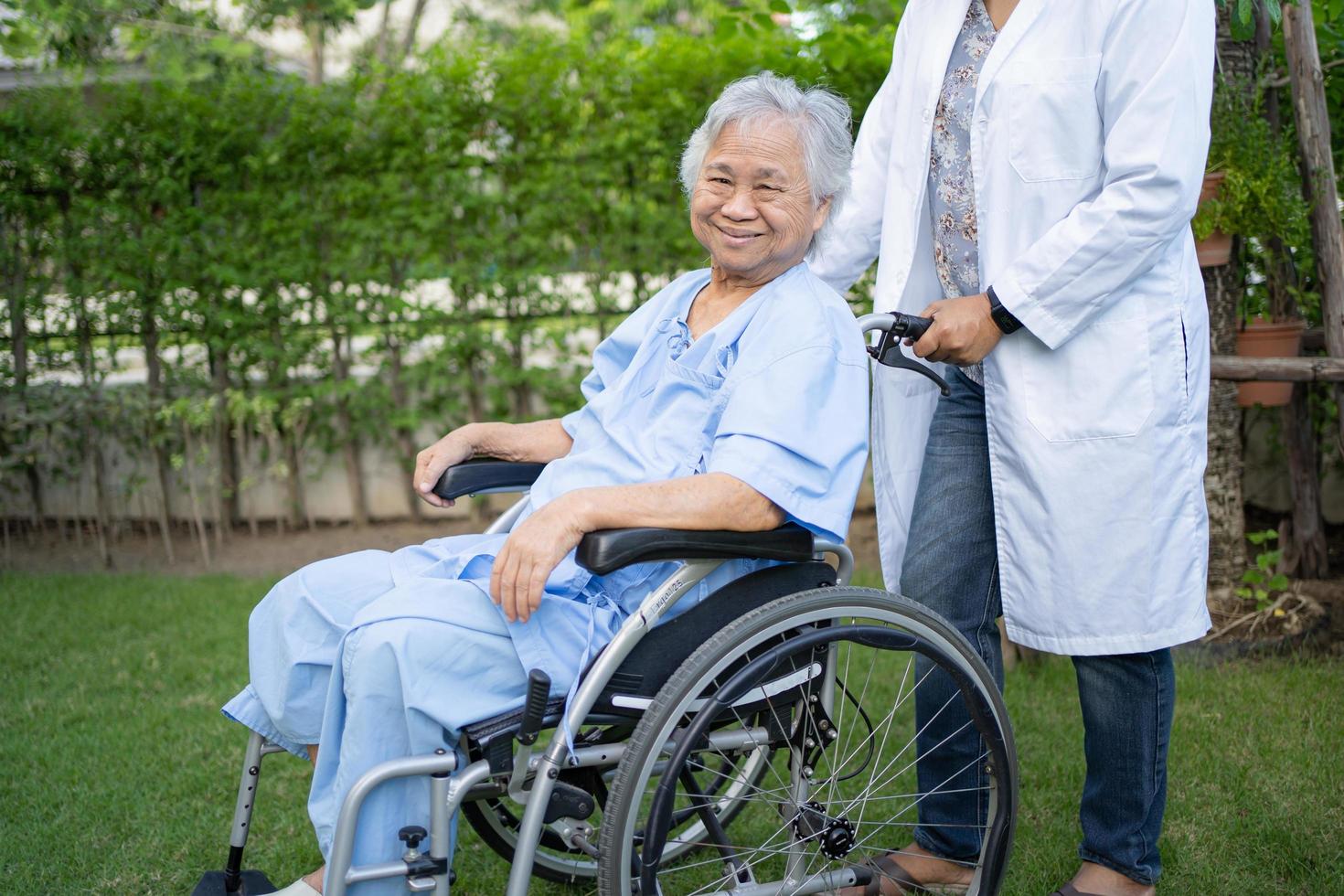 Arzt hilft und pflegt asiatische Senioren oder ältere Frauen, die auf Rollstuhl im Park in der Krankenstation sitzen, gesundes, starkes medizinisches Konzept. foto