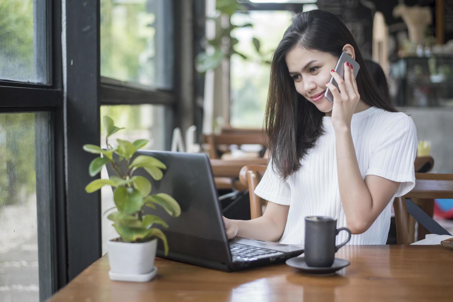 Schönes Geschäftsmädchen, das mit Tablet, Smartphone arbeitet und Kaffee im Café trinkt? foto