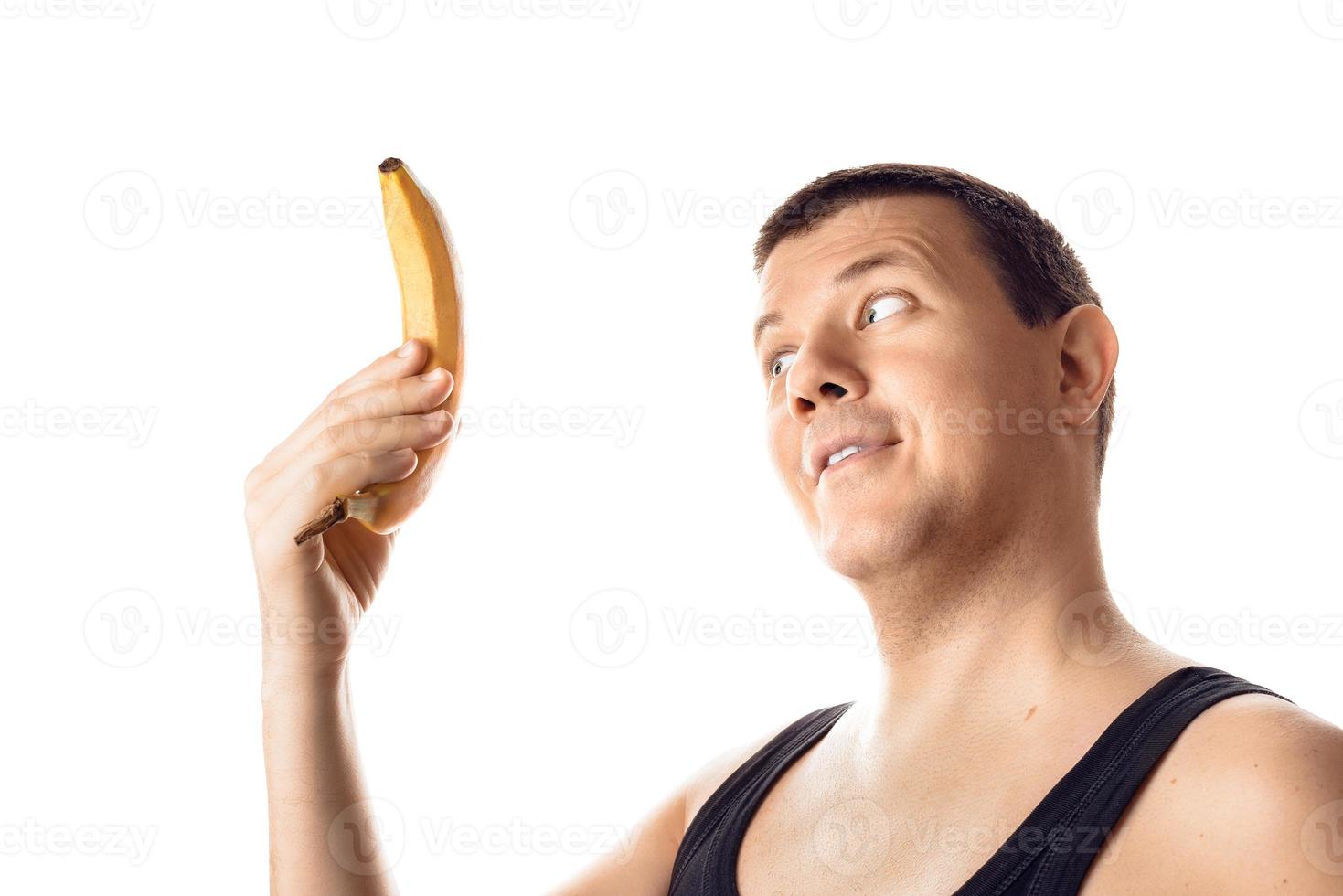 glücklicher junger zufriedener mann, der die banane betrachtet. menschliche Emotion, Reaktion, Ausdruck. isoliert auf weißem Hintergrund. foto