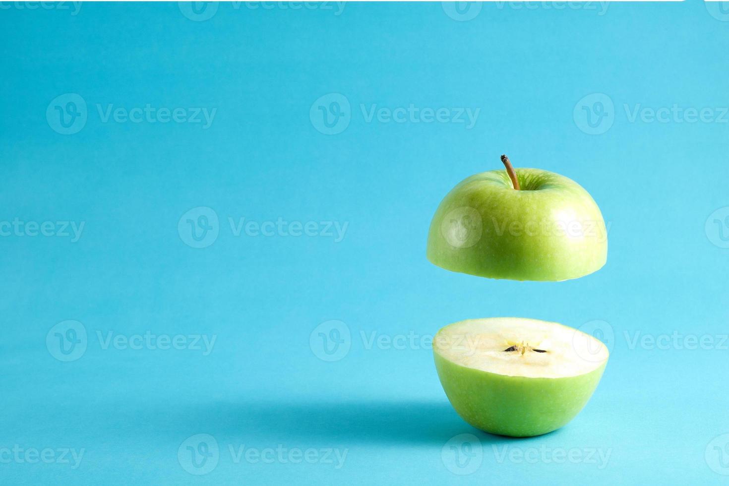 frischer grüner Apfel mit einem halben Fliegen auf blauem Hintergrund. Fliegender grüner Apfel mit leerem Kopienraum für Text. foto