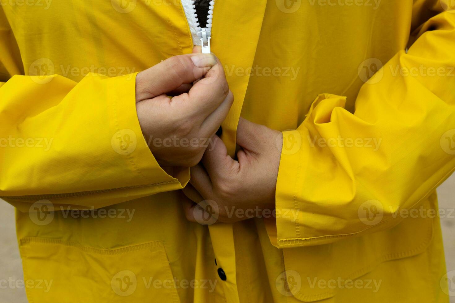 Gelb Regenjacke mit Weiß Reißverschluss Reißverschlüsse oben Jacke. foto