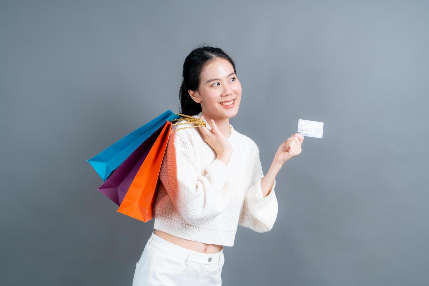 schöne asiatische Frau mit Einkaufstüten und mit Kreditkarte showing foto