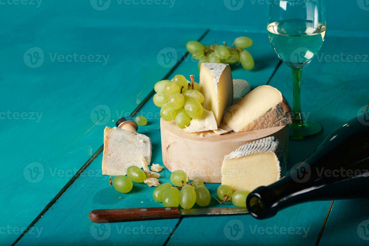 Käse, Trauben und Wein auf hölzern cyan Oberfläche. foto