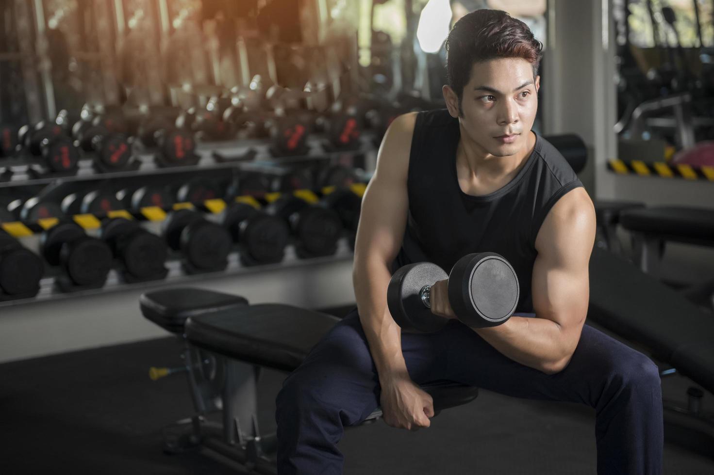 Mann mit Krafttrainingsgeräten am Sportgymnastikclub foto