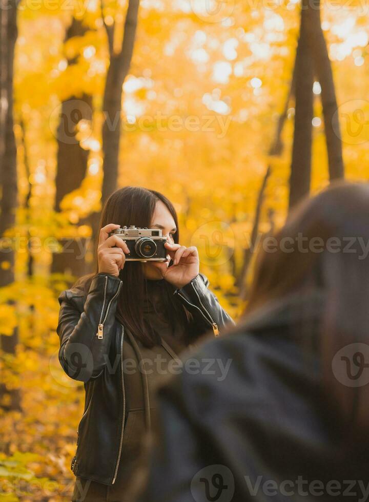 Mutter nehmen Bild ihr charismatisch Tochter auf retro Kamera im Herbst Park. Hobbys und Freizeit Konzept. foto