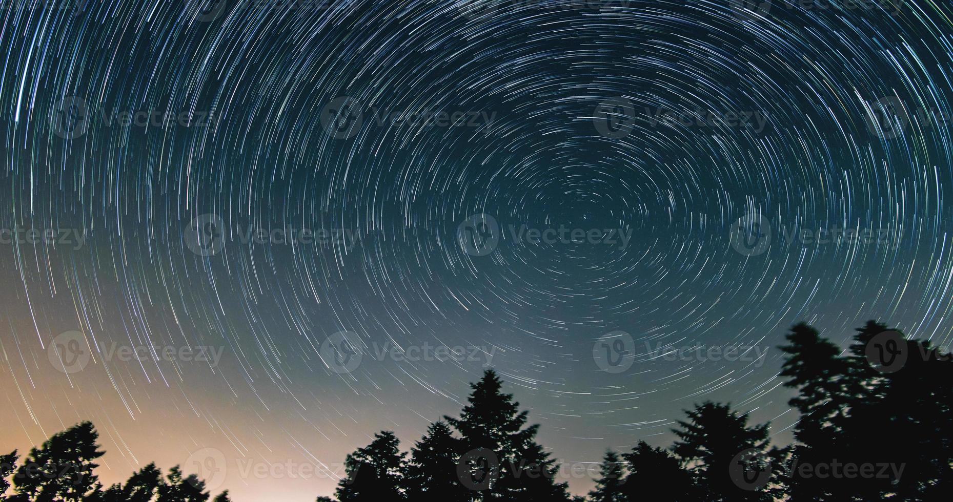 Sternspuren über dem Nachthimmel - Kometenmodus, Zeitraffer der Sternspur, Kiefern im Vordergrund, Avala, Belgrad, Serbien. der Nachthimmel ist astronomisch genau. foto