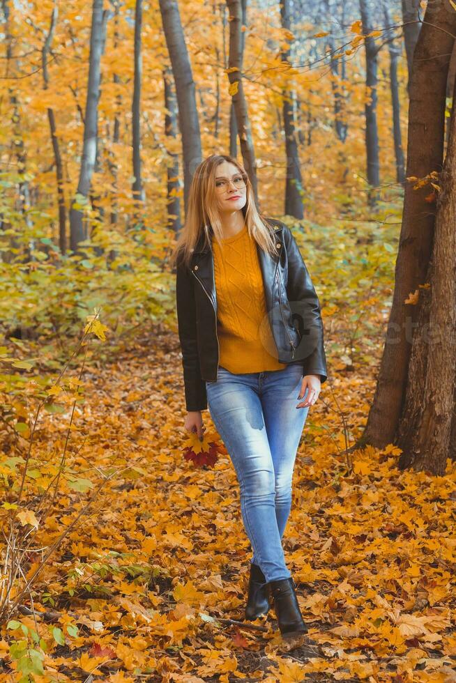 Mädchen hält gefallen Blätter und Spaziergänge im Herbst Park. saisonal Konzept. foto