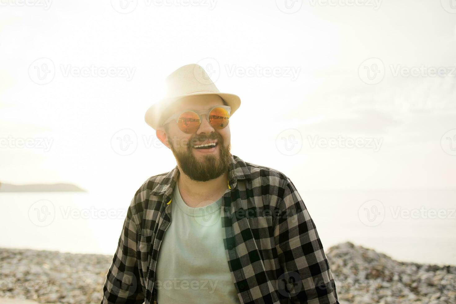 gut aussehend und zuversichtlich. draussen Porträt von lächelnd Mann tragen Hut und Sonnenbrille auf Strand leeren Raum zum Text. Ferien Reise und Sommer- Tourismus foto