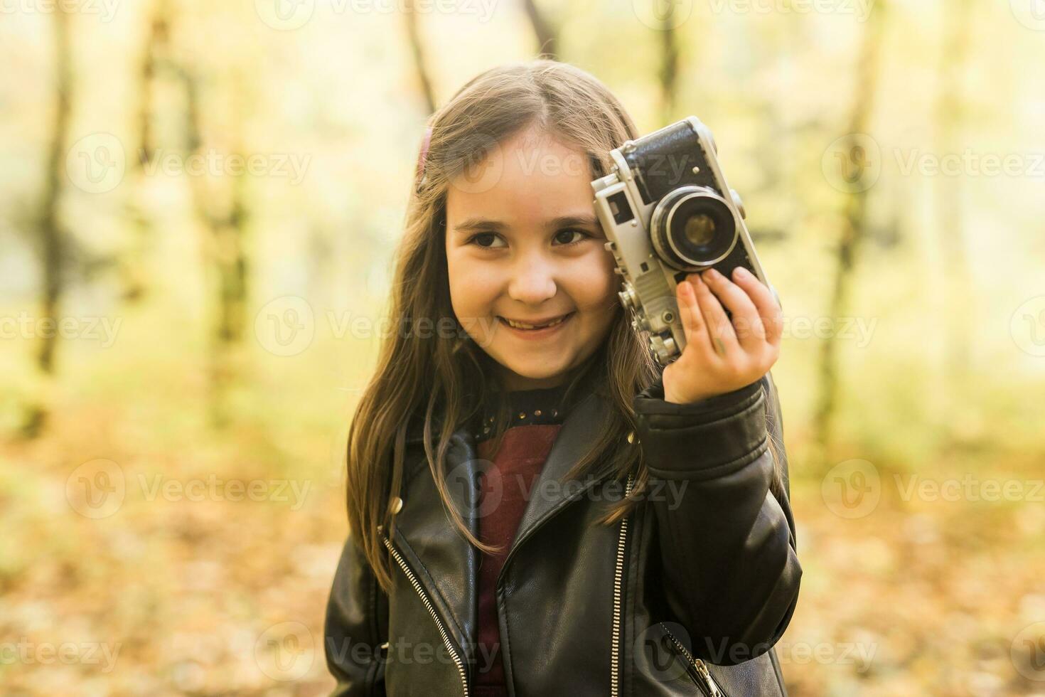 Kind Mädchen mit ein altmodisch Kamera im Herbst Natur. Fotograf, fallen Jahreszeit und Freizeit Konzept. foto