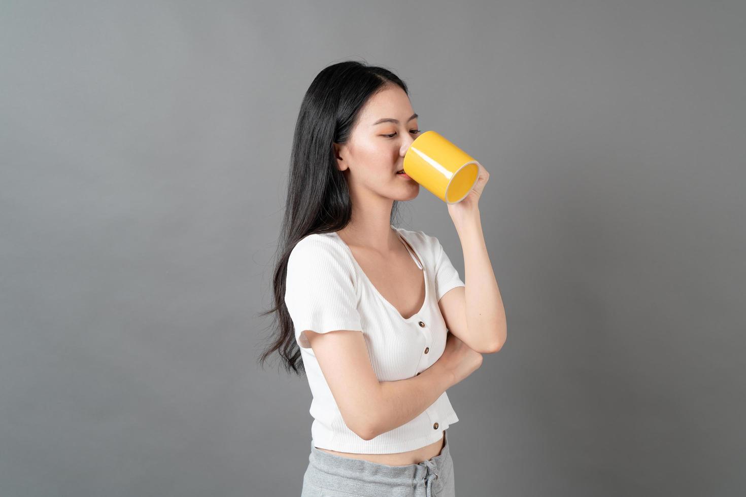 junge asiatische frau mit glücklichem gesicht und hand, die kaffeetasse hält foto