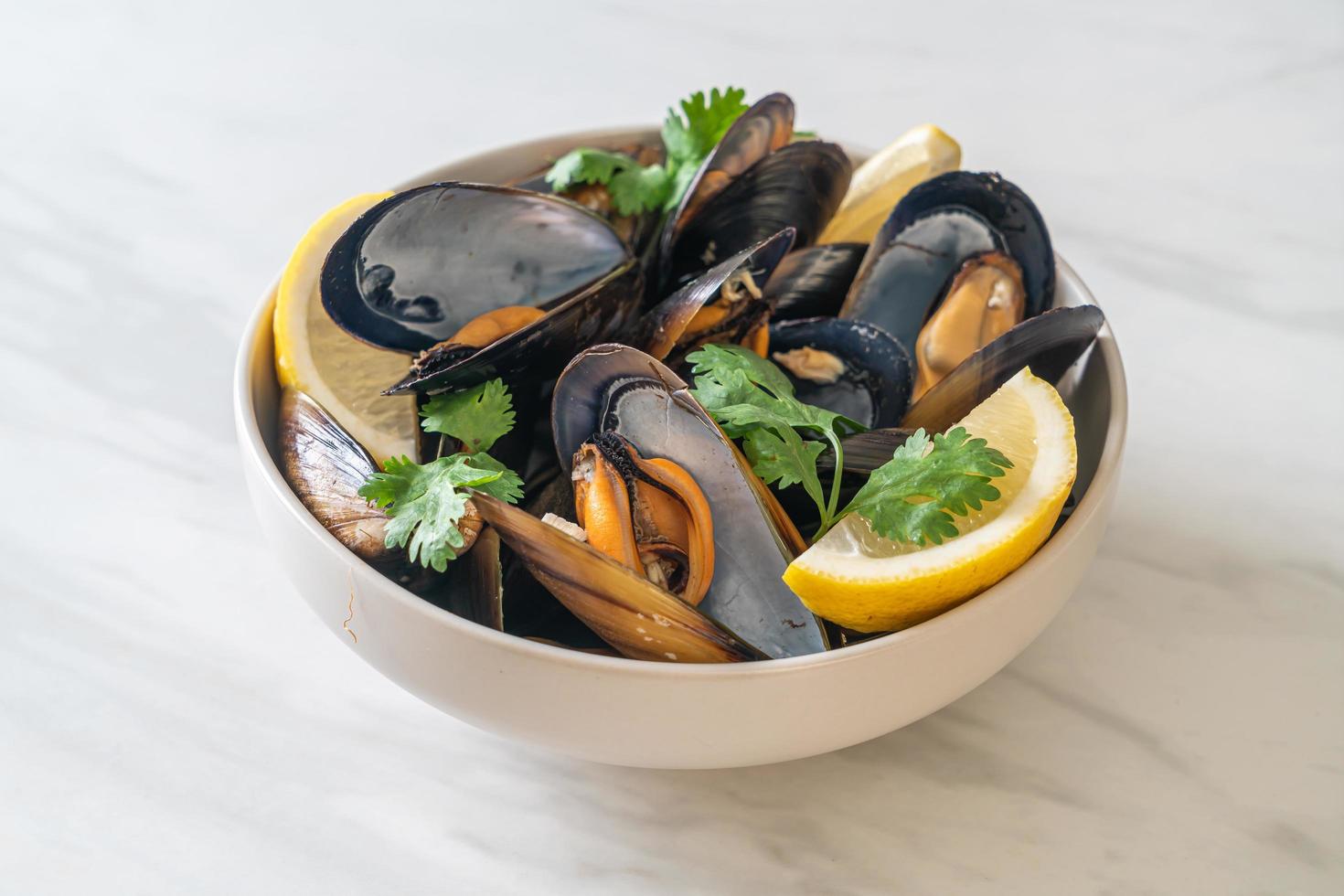 Muscheln mit Kräutern in einer Schüssel mit Zitrone foto