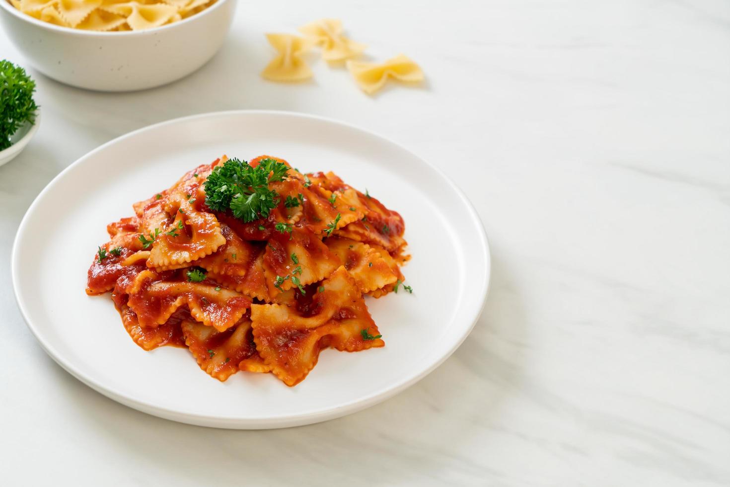 Farfalle-Nudeln in Tomatensauce mit Petersilie - italienische Küche foto