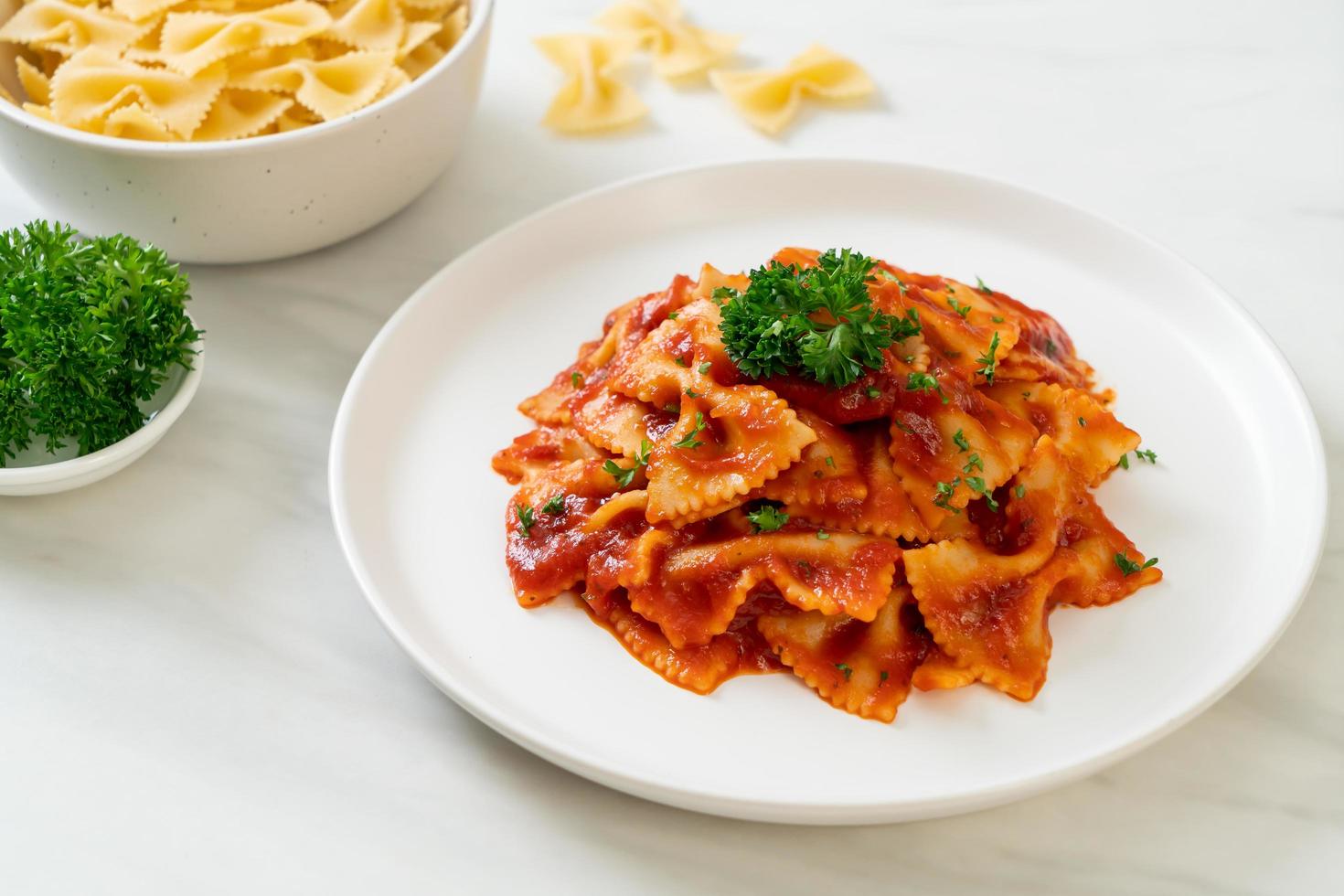 Farfalle-Nudeln in Tomatensauce mit Petersilie - italienische Küche foto