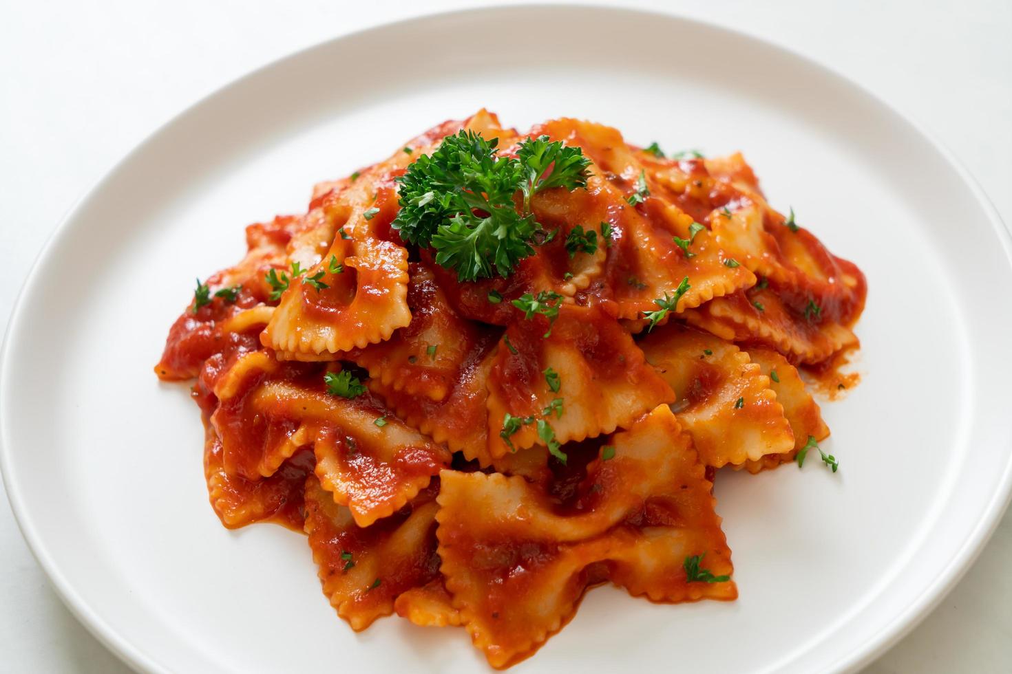 Farfalle-Nudeln in Tomatensauce mit Petersilie - italienische Küche foto