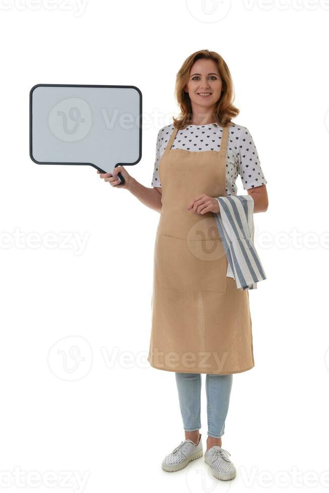 voll Länge Kellnerin halten ein Kreide Tafel. schön Frau im Barista Schürze mit Handtuch halten leeren Weiß Tafel auf Weiß Hintergrund isoliert foto