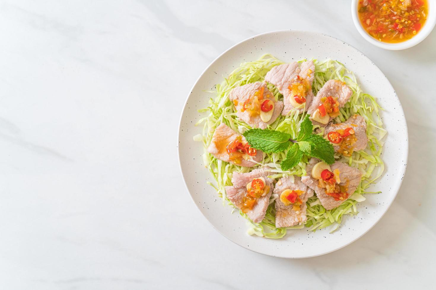 würziger Schweinesalat oder gekochtes Schweinefleisch mit Limetten-Knoblauch und Chilisauce foto