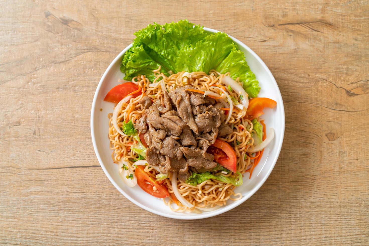 Instant-Nudel-Scharf-Salat mit Schweinefleisch auf einem weißen Teller - asiatische Küche foto