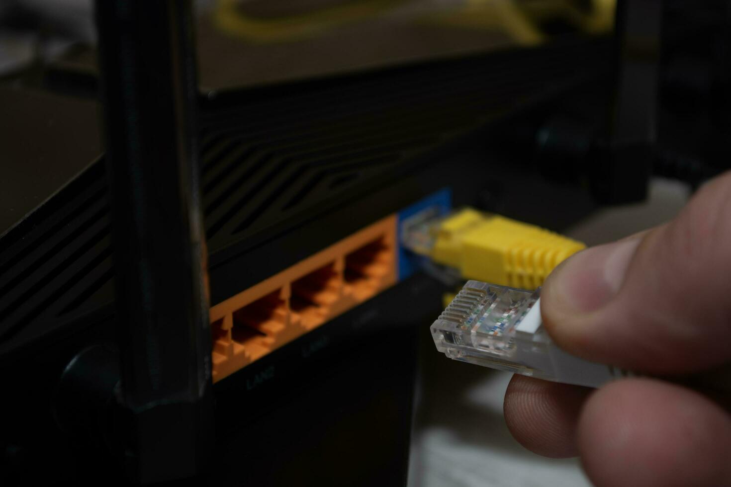 Nahansicht von ein des Mannes Hand, Finger verbinden ein Netzwerk Kabel zu ein Router. foto