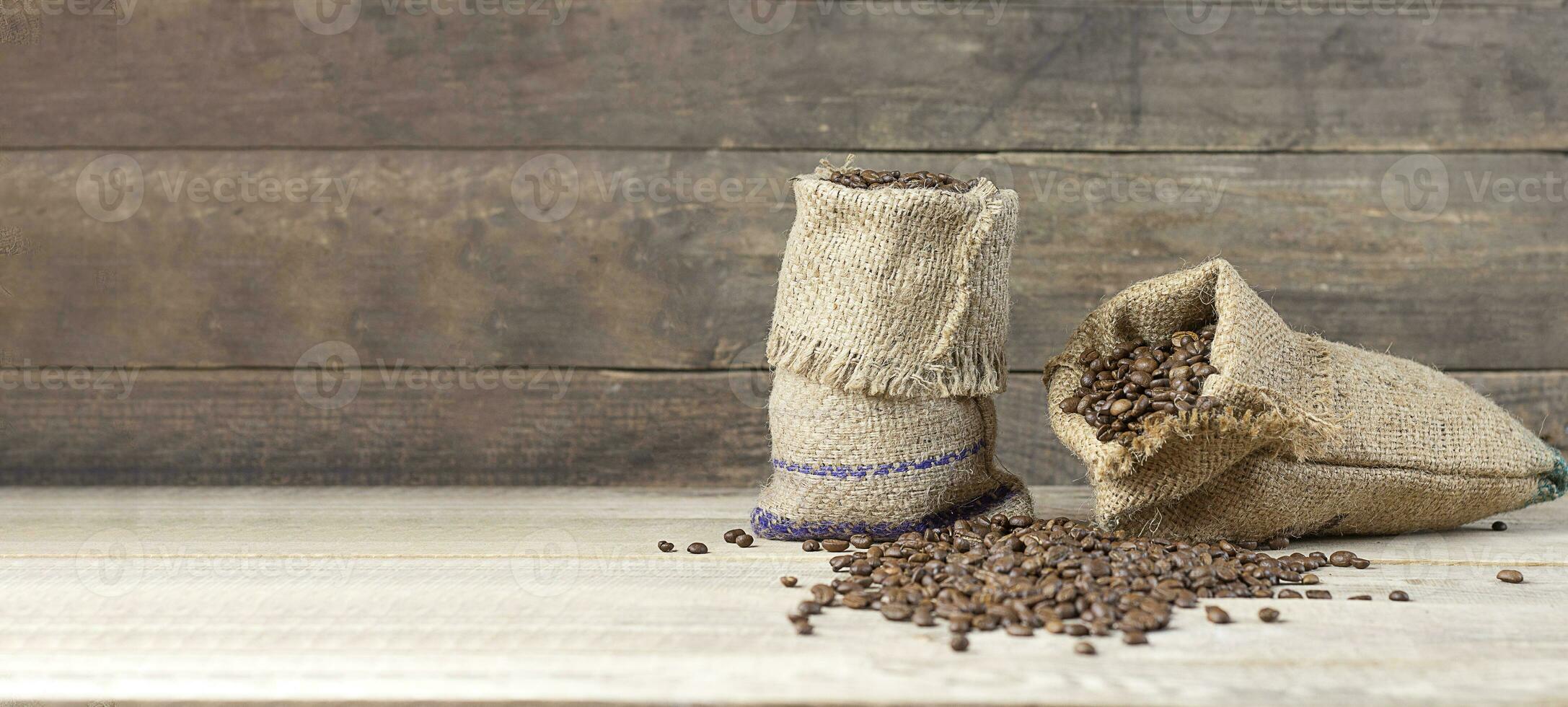 frisch Kaffee. Kaffee Bohnen im Taschen auf ein hölzern Hintergrund. Kopieren Raum. Banner foto
