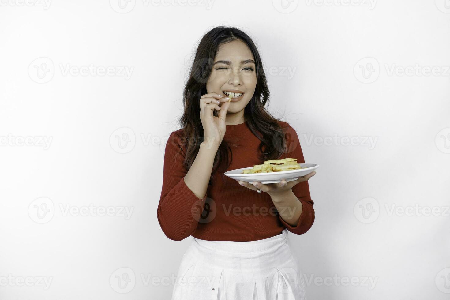 Bild von lächelnd jung asiatisch Mädchen Essen Französisch Fritten isoliert auf Weiß Hintergrund foto