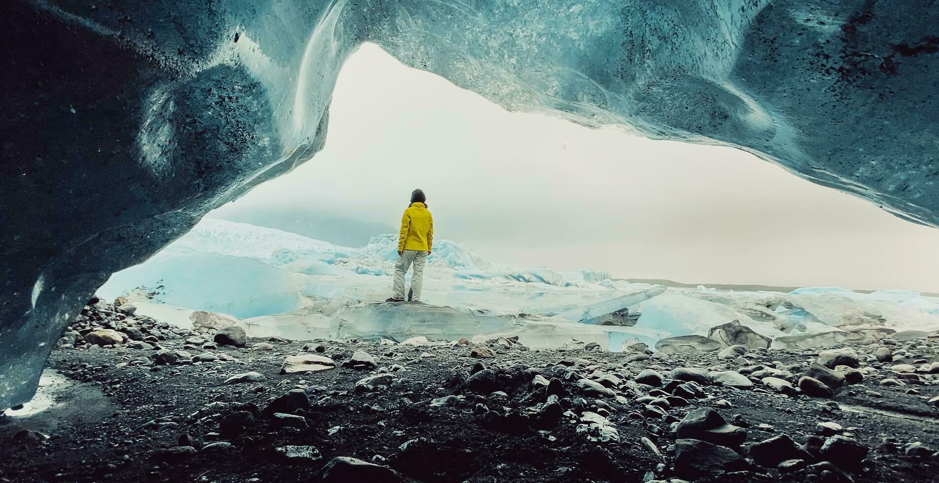 Tourist Reisender Frau Reise im Island Stand durch schön fjallsjökull Gletscher im Island im bedeckt Tag. filmisch Panorama von klein Spalt Eis Höhle foto