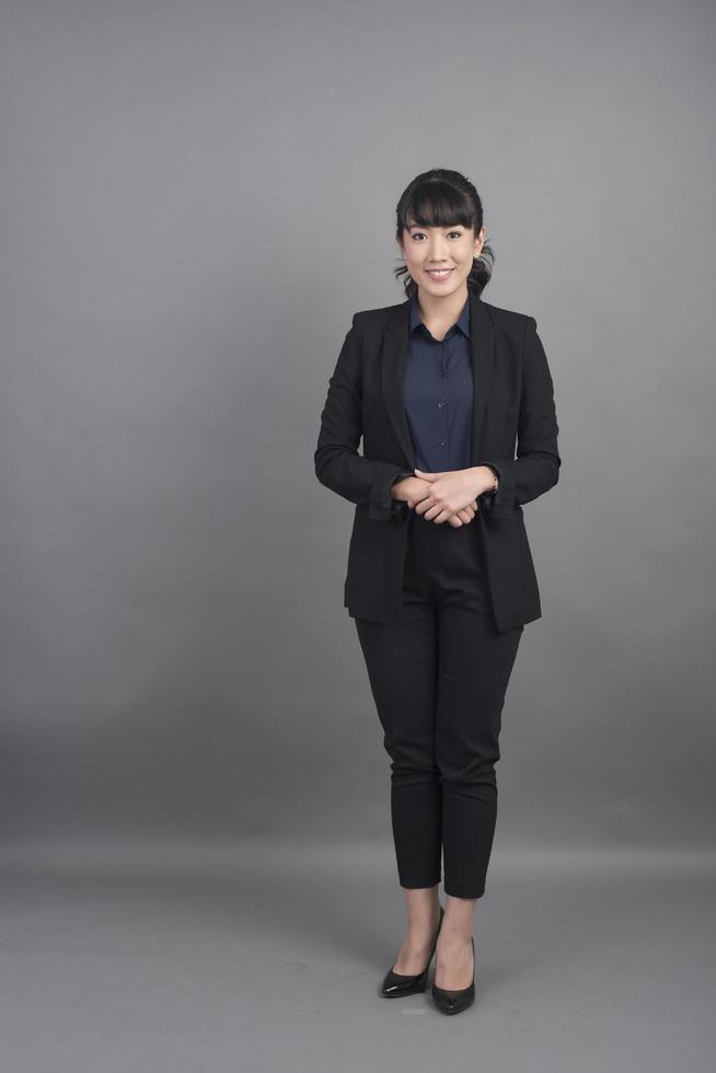 lächelnde Geschäftsfrau im Blazer auf grauem Hintergrund foto