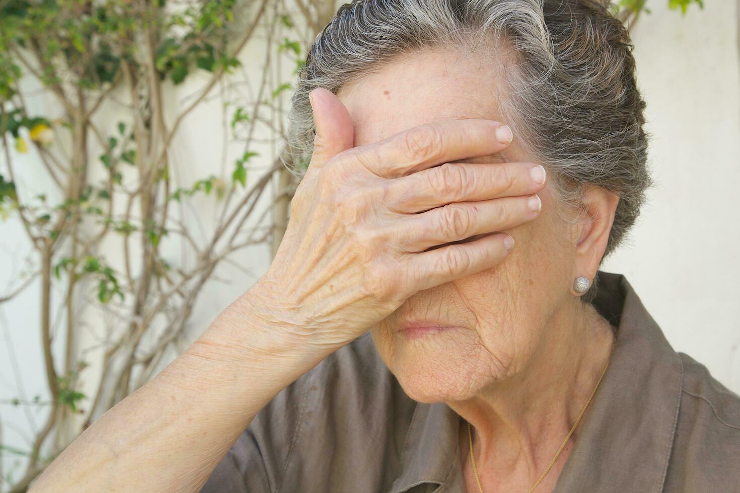 ein alt Frau schließen ihr Augen mit das Palme foto