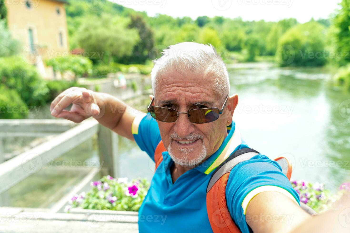gut aussehend Mitte alt Mann mit Weiß Spitzbart nehmen ein Selfie im das Straßen von ein Italienisch Dorf durch das See foto