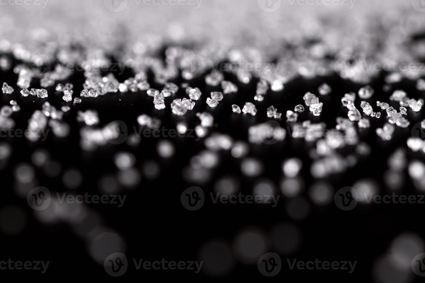 weißer Kristallzucker auf schwarzem Hintergrund foto