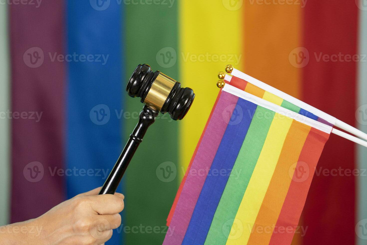 Hand von Fröhlich Stolz halten Holz Hammer oder Richter Hammer, und halten lgbt Flaggen Hintergrund verschwommen lgbtq Regenbogen Flagge, Konzept zum lgbt Anspruch Gerechtigkeit Rechte von Änderung, Recht, Diskriminierung, Gleichheit foto