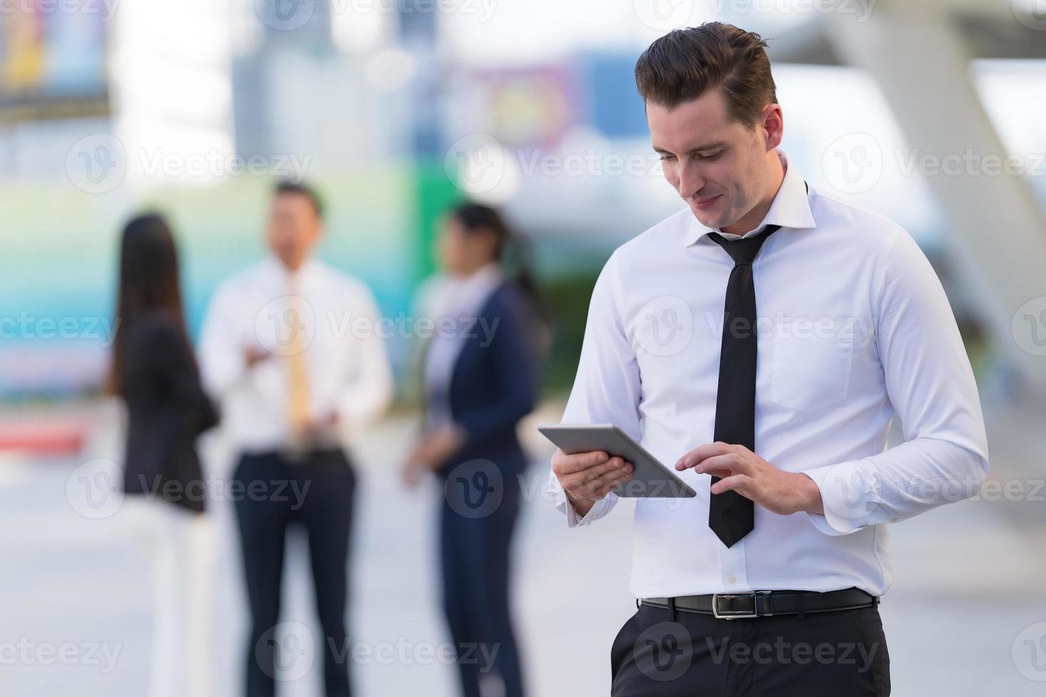 Geschäftsmann, der mit einem digitalen Tablet steht foto