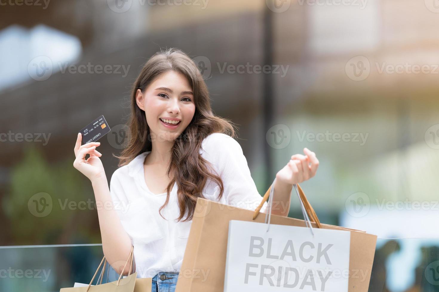 Black Friday Konzept, Frau hält viele Einkaufstüten mit Kreditkarte und lächelt foto