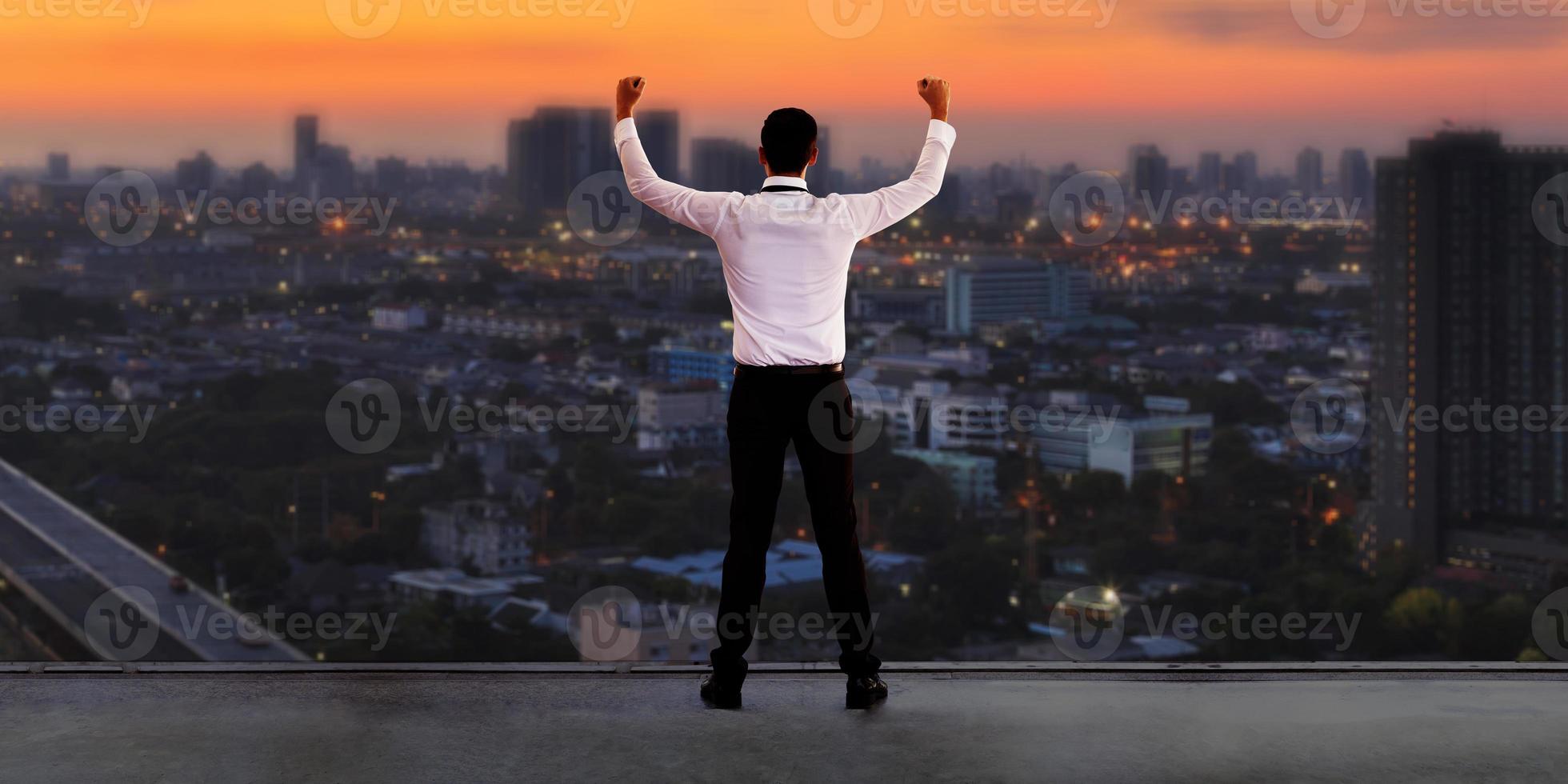 Geschäftsmann, der auf dem Dach steht und die Skyline des Stadtbilds betrachtet foto