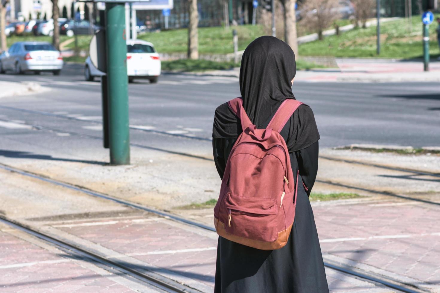 muslimische frau, die auf eine straßenbahn wartet foto